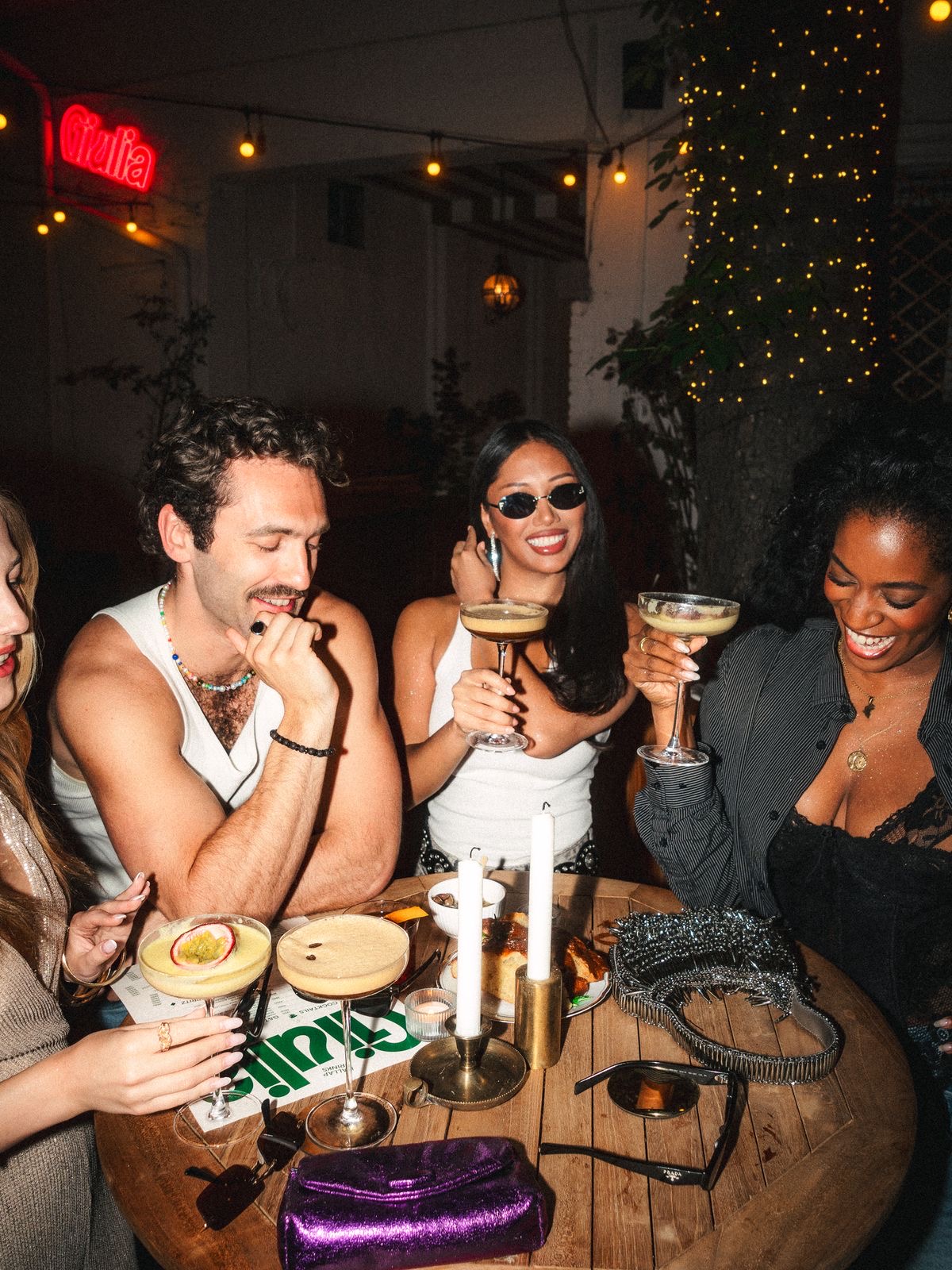 Freundinnen und Freunde mit Cocktails am Tisch